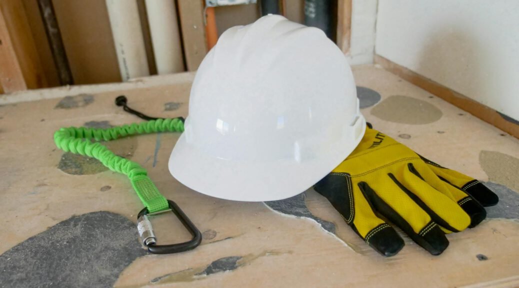 Statybininkas su viso kūno saugos diržais ir šalmu, dirbantis aukštyje.